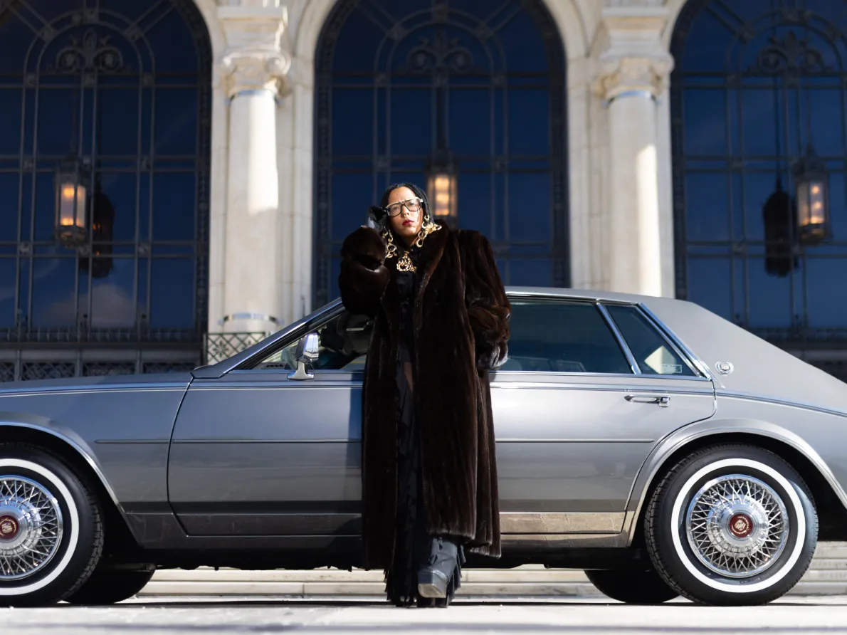 Tiff Massey exhibition. Tiff is standing next to a car in front of the Detroit Institute of Arts.