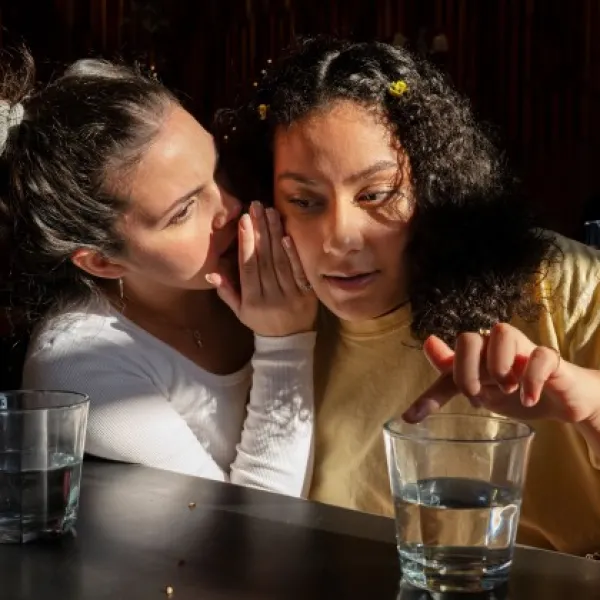 Young girl whispers to adult female